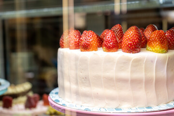 Strawberry-yogurt fresh cake on a bakery sail behind a glass. The temptation to diet. Close-up