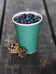 Fototapeta na wymiar Fresh blueberries in a paper cup on a wooden table.