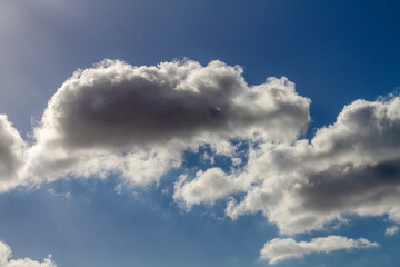 Beautiful puffy clouds in the rays of the sun on a blue sky.