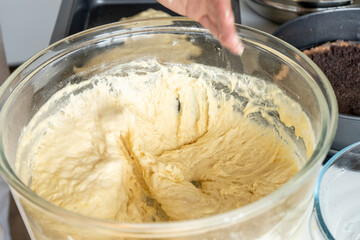 Fototapeta premium Woman and dough in the glass bowl in the kitchen. Cooking cupcakes. Close-up