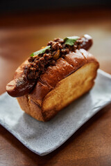 plate with baked bread and sausage on wooden table, close view hot dog