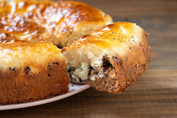 A piece of freshly baked golden crust pie on a pink plate on a brown wooden table on the right. Close-up