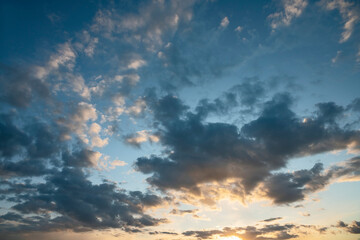sun sets behind the clouds in the blue evening sky as a natural background