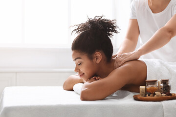Pretty black woman enjoying body massage with aromatherapy
