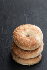 Stack of sesame seed bagels isolated on black stone background
