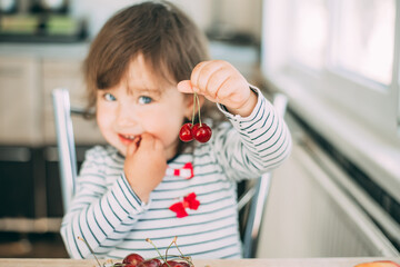 Little Girl in the kitchen eating delicious cherries