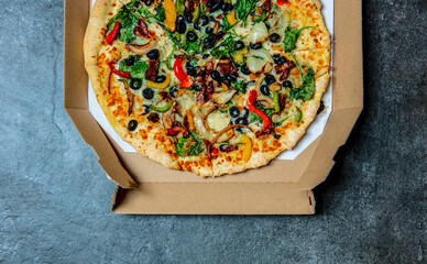 mediterranean Pizza with olives and cheese in cardboard on a table