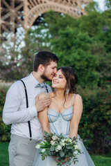The groom kisses the bride, on their wedding day in Paris, under the Eiffel tower, she smiles.