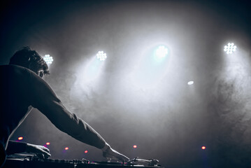 DJ in headphones plays at the club. disco. night life. atmosphere. black-and-white photo