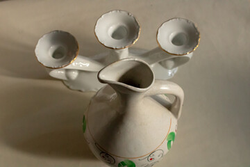 Decorative porcelain jug with a handle and a candlestick on a cloudy day.