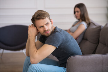 Young couple sitting on the sofa after a quarrel