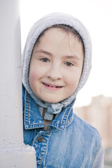 Cute Caucasian teenage girl in a denim jacket and a hood. Vertical shot