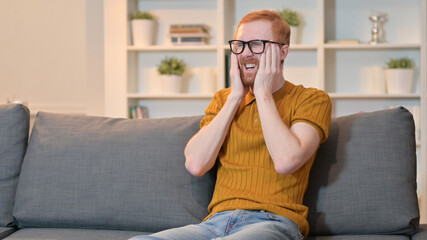 Exhausted Redhead Man having Headache at Home 