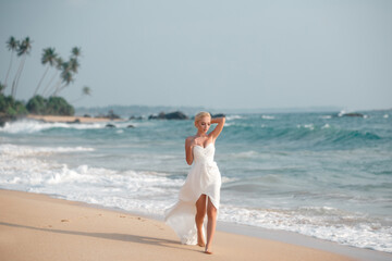 Fototapeta na wymiar Beautiful model in white dress by the sea. Concept of wedding and bridal morning