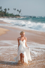 Fototapeta na wymiar Wedding photo session beautiful bride blonde in a wedding dress walkng sandy tropical beach. Sea weddding concept