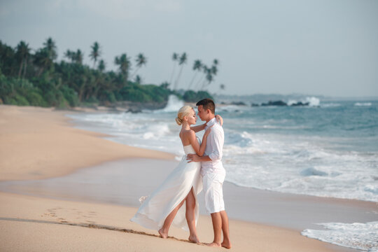 Beautiful wedding couple outdoor portrait. Photography with young pretty bride with groom on natural tropical beach and sea background. Just married, love and family concept