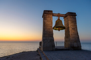 Famous Bell of Chersonesos (sygnal fog bell) on the grounds of ancient Greek colony Chersonesos by Black sea at sunset, Crimea