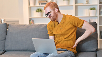 Redhead Man with Back Pain Working on Laptop at Home 