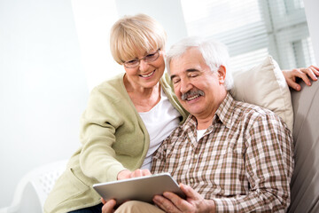 Elderly couple have fun at home with a tablet computer