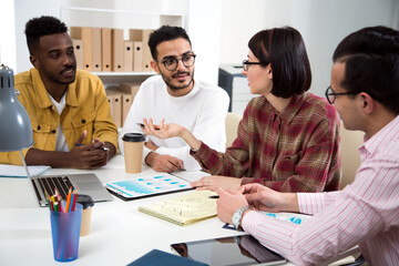Multy-ethnic group of young business people sitting at the office desk and working with computer.