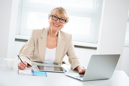 Portrait of mature business woman looking at camera at workplace in an office