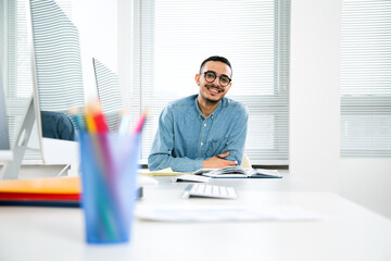 Fototapeta na wymiar Happy arab creative businessman smiling while looking at camera in office