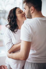 Stunning sensual intdoor portrait of young stylish fashion couple in love. Woman and man embrace and want to kiss each other. They are smiling and looking to each other