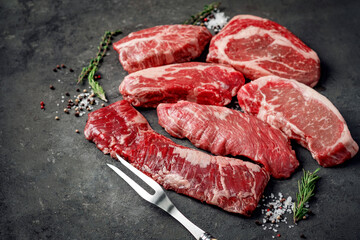 A set of different types of raw beef steaks: rib eye, Striploin, Denver, machete, top blade on a...