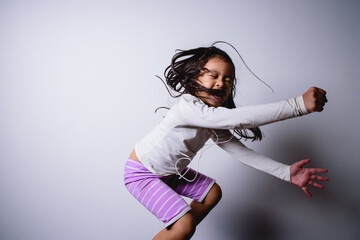 Portrait of happy little Asian child girl jumping listen music  white background