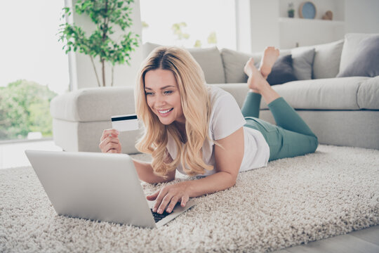 Photo Of Domestic House Wife Lady Relaxing Lying Floor Near Couch Browsing Notebook Remote Work Hold Credit Card Make Inline Shopping Purchase Stay Home Quarantine Time Living Room Indoors