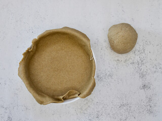 Rye dough for open pie in ceramic baking dish on white background. Home baking concept. Top view