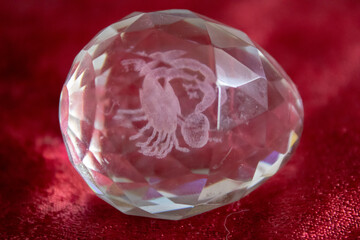 A glass egg with iridescent faces and inside the zodiac sign Scorpio.