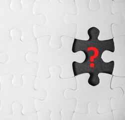 White puzzle with missing piece and question mark on black background, top view