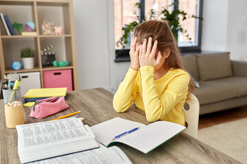 children, education and learning concept - stressed little student girl with book and notebook at home