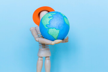 Ecology concept, wooden man and globe on the blue background.