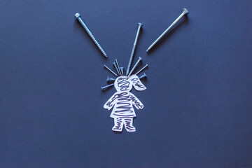 Pain concept, paper woman and nails on the dark background.