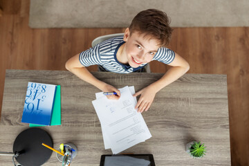 education, school and learning concept - happy smiling student boy writing test at home