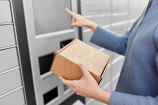 mail delivery and post service concept - close up of happy smiling woman with box at outdoor automated parcel machine choosing operation on touch screen