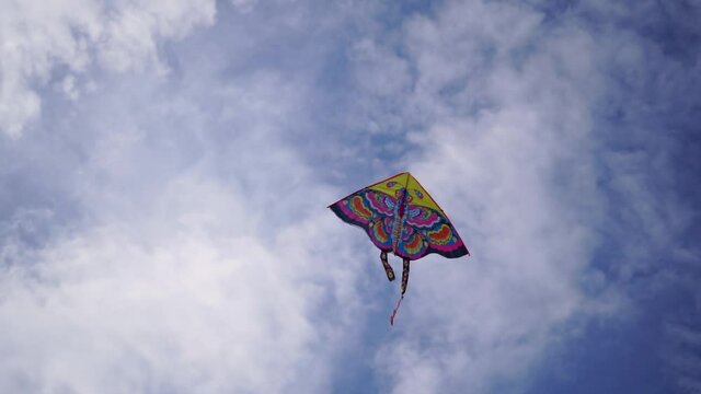 Flying kite in blue sky with clouds. Summer outdoor activity. Freedom, carefree, happiness concept