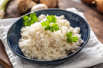 Bowl of steamed rice with mushrooms and leaks in the background