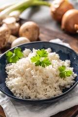 Bowl of steamed rice with mushrooms and leaks in the background