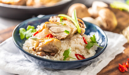Plate of steamed rice, chicken chilli and spring onions on a table with more ingredients in the background