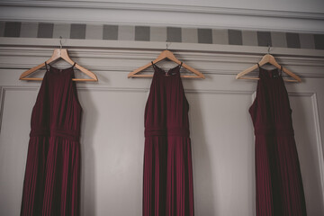 Dark red bridesmaid dresses hanging on a wardrobe