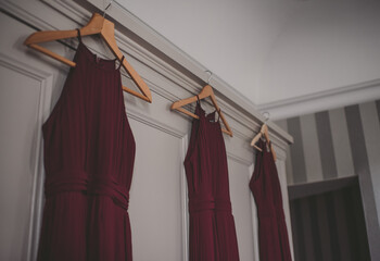 Dark red bridesmaid dresses hanging on a wardrobe