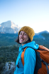 Portrait of a smiling girl with a backpack on a background of mountains.