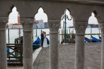 beautiful wedding couple posing on dock near blue gondolas 