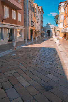 Fototapeta Streets in the old town of Zadar, Croatia. The famous Sea Gate to the marina in the background