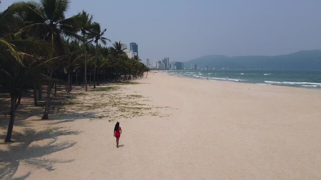 Aerial view of a young woman walking in the empty tropical city beach in Vietnam