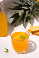 Fermented kombucha pineapple summer drink on a white plate next to the ingredients. Vertical photo