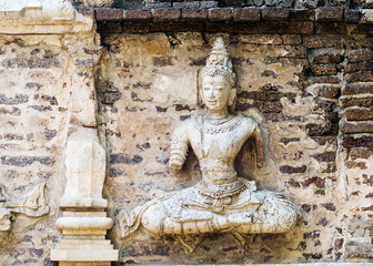 Old damaged stucco reliefs carvings of Buddha on the facade of Maha chedi, Wat Chet Yot, Chiang Mai, Thailand